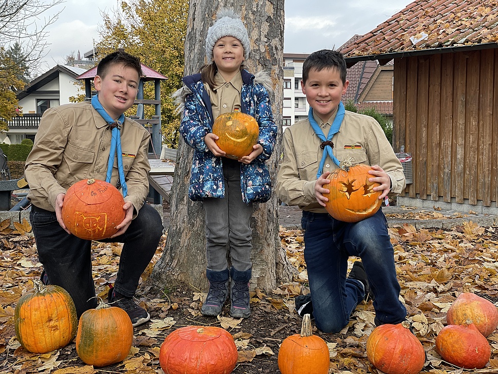 Drei Kinder halten Kürbisse hoch